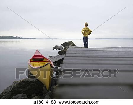 Stock Image - Young boy on a dock near a boat.. Fotosearch