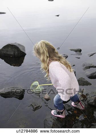 Stock Photograph - Young girl fishing in a lake with a net.. Fotosearch