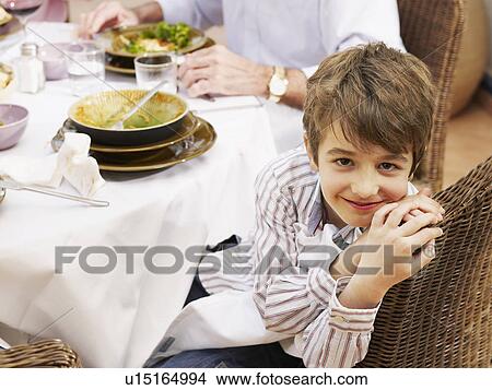 Boy (6-8) at family meal in garden, smiling, portrait View Large Photo Image Picture - Boy (6-8) at family meal in garden, smiling, portrait. Fotosearch