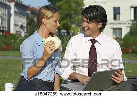 Businessman and businesswoman sitting in park working. View Large Photo Image Stock Photo - Businessman and businesswoman sitting in park working.. Fotosearch