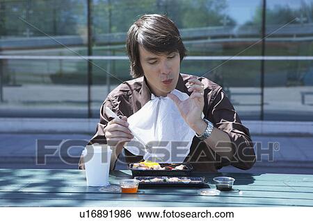 Businessman eating sushi outside with chopsticks licking off finger. View Large Photo Image Stock Photograph - Businessman eating sushi outside with chopsticks licking off finger.. Fotosearch