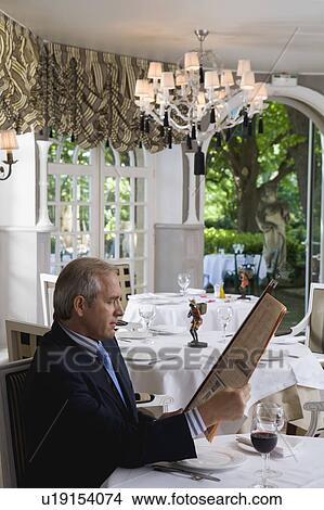 Businessman having lunch reading a financial paper View Large Photo Image Picture - Businessman having lunch reading a financial paper. Fotosearch