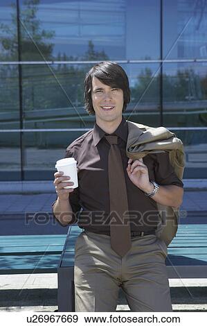 Businessman leaned on table in front of office with coffee to go smiling. View Large Photo Image Stock Photo - Businessman leaned on table in front of office with coffee to go smiling.. Fotosearch
