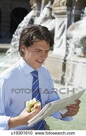 Businessman sitting on fountain with newspaper and burger laughing. View Large Photo Image Stock Image - Businessman sitting on fountain with newspaper and burger laughing.. Fotosearch