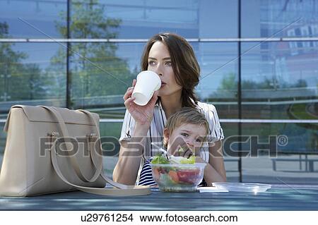 Businesswoman and her child eating lunch together outside. View Large Photo Image Picture - Businesswoman and her child eating lunch together outside.. Fotosearch