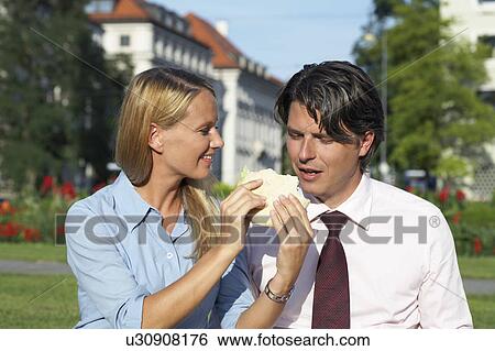 Businesswoman feeding sandwich to businessman. View Large Photo Image Stock Photograph - Businesswoman feeding sandwich to businessman.. Fotosearch