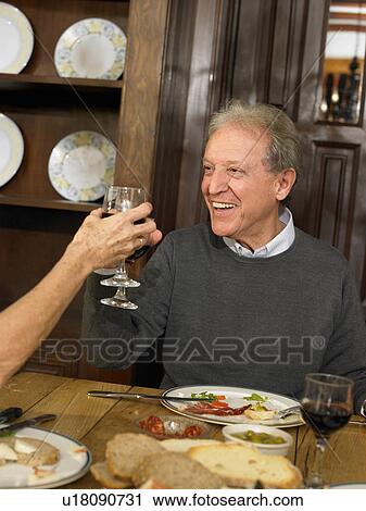 Senior man toasting glass of red wine at lunch, smiling View Large Photo Image Stock Image - Senior man toasting glass of red wine at lunch, smiling. Fotosearch