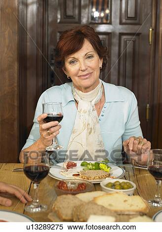 Senior woman at lunch table holding glass of red wine, portrait. Alicante, Spain. View Large Photo Image Stock Photography - Senior woman at lunch table holding glass of red wine, portrait. Alicante, Spain.. Fotosearch