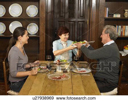 Stock Photo - Young woman and senior parents having lunch, smiling. Fotosearch