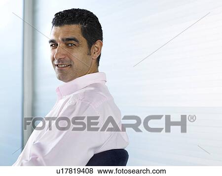Businessman sitting in office, smiling, portrait View Large Photo Image Stock Photo - Businessman sitting in office, smiling, portrait. Fotosearch