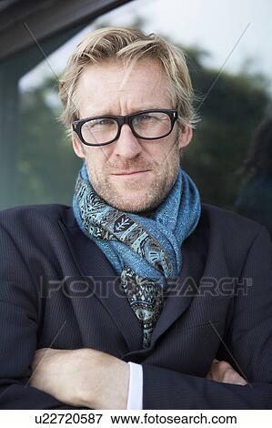Businessman wearing extravagant scarf leaning against window with glasses. View Large Photo Image Stock Photo - Businessman wearing extravagant scarf leaning against window with glasses.. Fotosearch