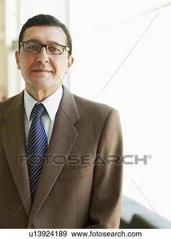 Stock Photo - Mature businessman standing in office, portrait. Fotosearch