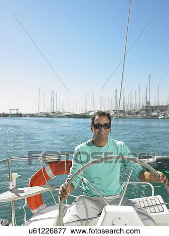 Mature man wearing sunglasses steering yacht, smiling View Large Photo Image Stock Photo - Mature man wearing sunglasses steering yacht, smiling. Fotosearch