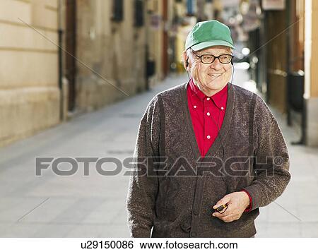 Senior man standing in street wearing earphones, smiling View Large Photo Image Stock Photograph - Senior man standing in street wearing earphones, smiling. Fotosearch