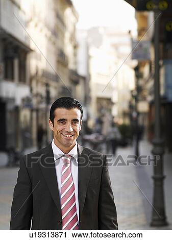 Young businessman standing in street, smiling View Large Photo Image Stock Image - Young businessman standing in street, smiling. Fotosearch