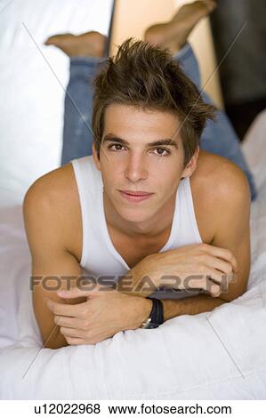 Young man lays on bed portrait. View Large Photo Image Stock Photo - Young man lays on bed portrait.. Fotosearch