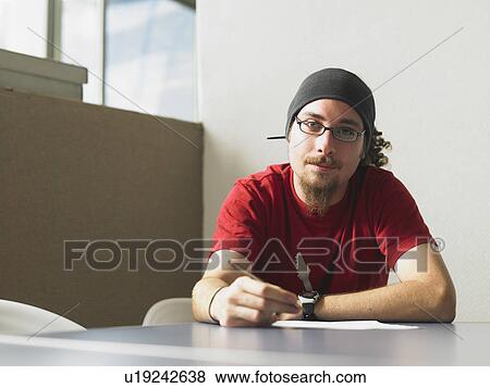 Young man sitting at desk portrait View Large Photo Image Stock Photo - Young man sitting at desk portrait. Fotosearch