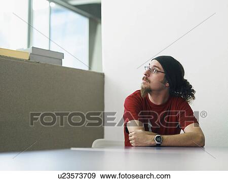 Stock Photo - Young man sitting at desk portrait. Fotosearch