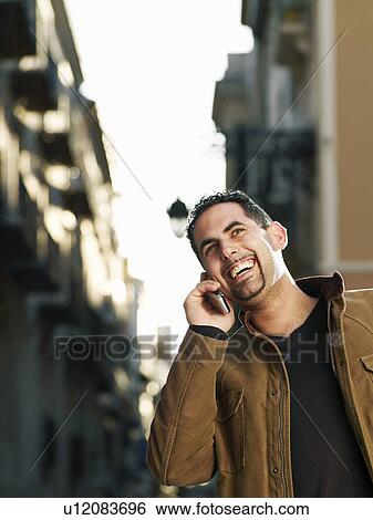 Young man using mobile phone in street, smiling View Large Photo Image Stock Photograph - Young man using mobile phone in street, smiling. Fotosearch