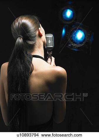 Picture - Back of woman singing into microphone.. Fotosearch
