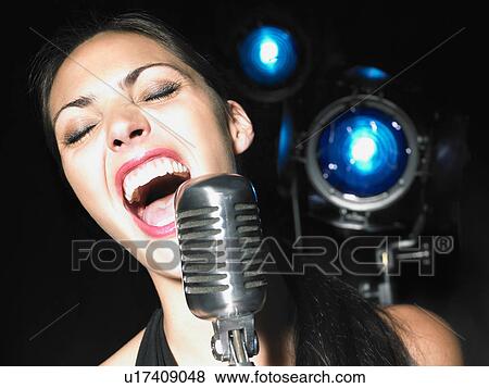 Close up of woman singing into microphone. View Large Photo Image Stock Photo - Close up of woman singing into microphone.. Fotosearch
