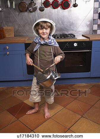 Stock Image - Little boy in kitchen drumming.. Fotosearch