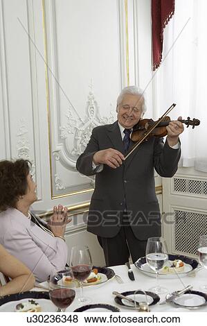 Stock Photo - Senior man playing violin to woman. Fotosearch