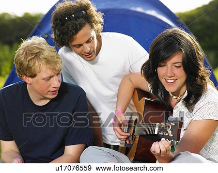 Two young men watching girl playing guitar View Large Photo Image Stock Photo - Two young men watching girl playing guitar. Fotosearch