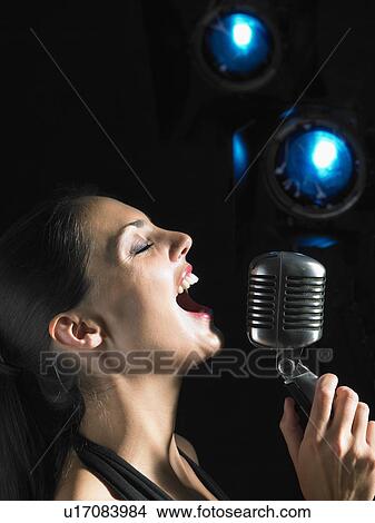 Woman singing into microphone. View Large Photo Image Picture - Woman singing into microphone.. Fotosearch