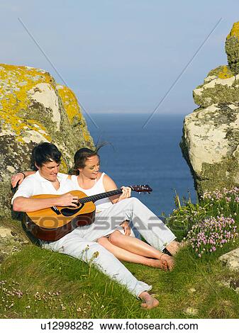 Young couple on a cliff playing guitar. View Large Photo Image Stock Image - Young couple on a cliff playing guitar.. Fotosearch