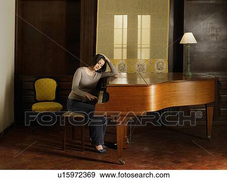 Young woman playing piano, resting elbow on piano View Large Photo Image Stock Photo - Young woman playing piano, resting elbow on piano. Fotosearch