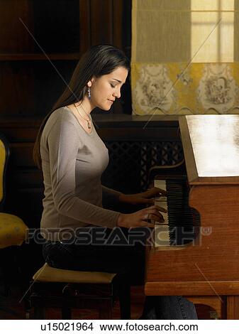 Picture - Young woman playing piano, side view. Fotosearch