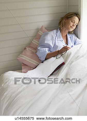 Stock Photography - Businesswoman resting with work on bed. Fotosearch