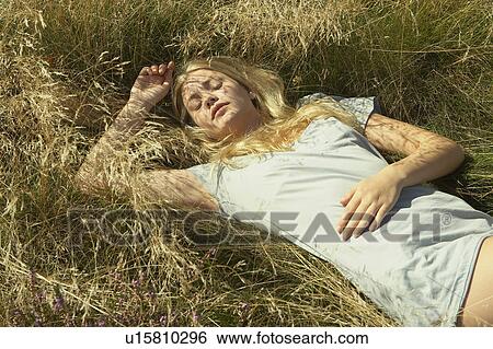 Young woman lying in long grass. View Large Photo Image Stock Photograph - Young woman lying in long grass.. Fotosearch