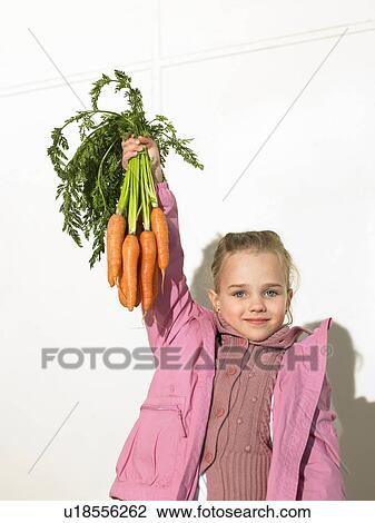 Girl (5-7) holding bunch of carrots, portrait View Large Photo Image Stock Image - Girl (5-7) holding bunch of carrots, portrait. Fotosearch