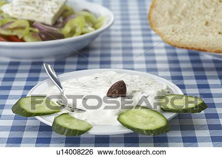 Greek tsatsiki salad decorated with cucumber on table Greek salad and bread in background View Large Photo Image Stock Photograph - Greek tsatsiki salad decorated with cucumber on table Greek salad and bread in background. Fotosearch