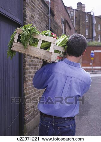 Stock Image - Man with a crate of vegetables . Fotosearch