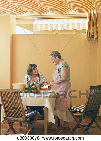 Senior woman preparing food at home, adult daughter looking on View Large Photo Image Stock Photo - Senior woman preparing food at home, adult daughter looking on. Fotosearch