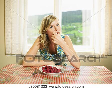 Woman eating bowl of raspberries at table. View Large Photo Image Stock Image - Woman eating bowl of raspberries at table.. Fotosearch