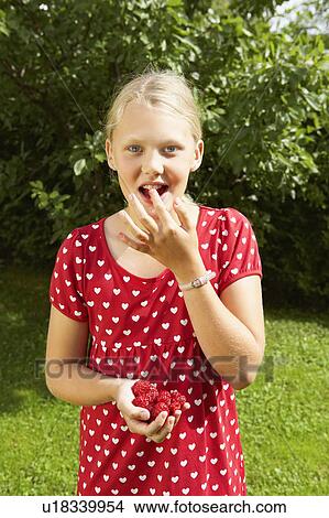 Young girl eating fresh raspberries outdoors. View Large Photo Image Picture - Young girl eating fresh raspberries outdoors.. Fotosearch