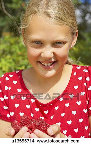 Young girl outdoors smiling holding fresh raspberries. View Large Photo Image Picture - Young girl outdoors smiling holding fresh raspberries.. Fotosearch
