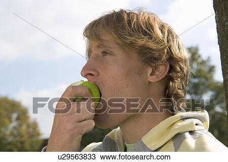 Young man eating apple. View Large Photo Image Stock Image - Young man eating apple.. Fotosearch