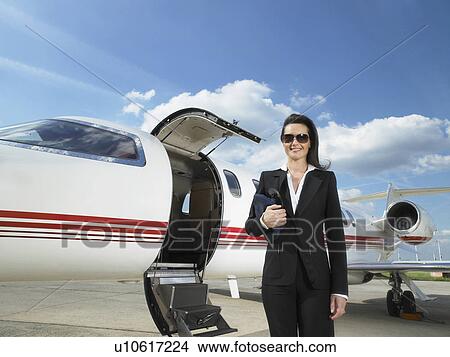 Female pilot standing next to private jet. View Large Photo Image Picture - Female pilot standing next to private jet.. Fotosearch