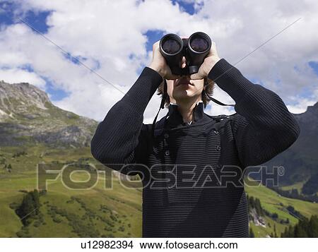 Man looking through his binoculars. View Large Photo Image Picture - Man looking through his binoculars.. Fotosearch