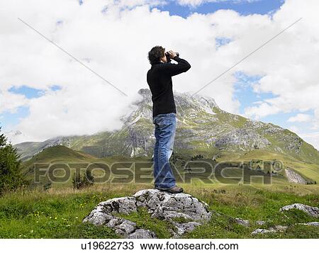 Man looking through his binoculars. View Large Photo Image Stock Image - Man looking through his binoculars.. Fotosearch