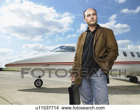Man standing in front of private jet. View Large Photo Image Picture - Man standing in front of private jet.. Fotosearch