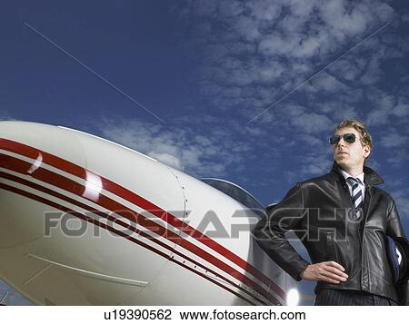 Pilot standing next to private jet. View Large Photo Image Stock Image - Pilot standing next to private jet.. Fotosearch