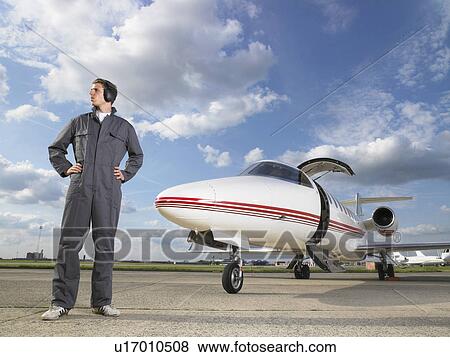 Technician in gray overall standing in front of private jet on tarmac. View Large Photo Image Stock Photo - Technician in gray overall standing in front of private jet on tarmac.. Fotosearch