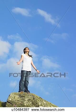 Woman standing on cliff with her arms out. View Large Photo Image Stock Photo - Woman standing on cliff with her arms out.. Fotosearch