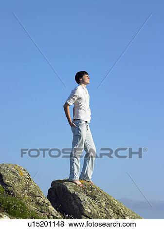 Young man standing on cliff. View Large Photo Image Stock Photo - Young man standing on cliff.. Fotosearch